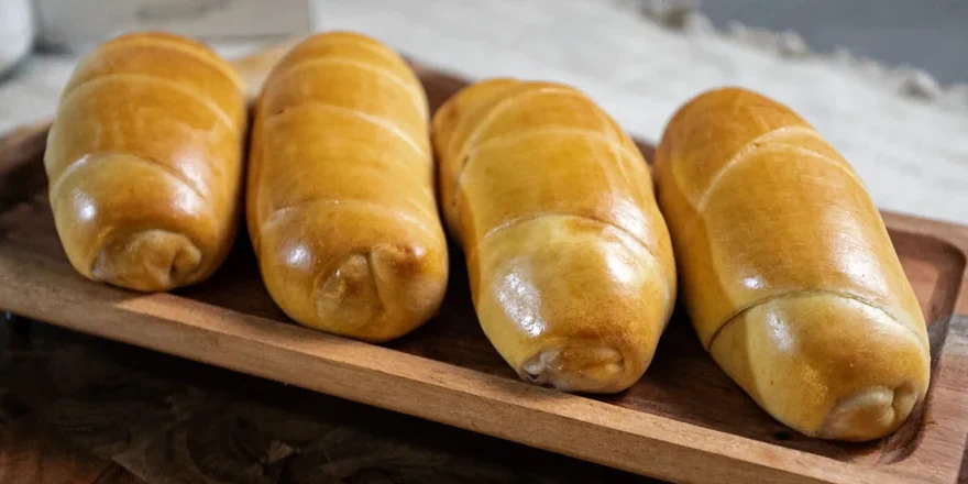 Cuatro cachitos de jamón dorados sobre una bandeja de madera